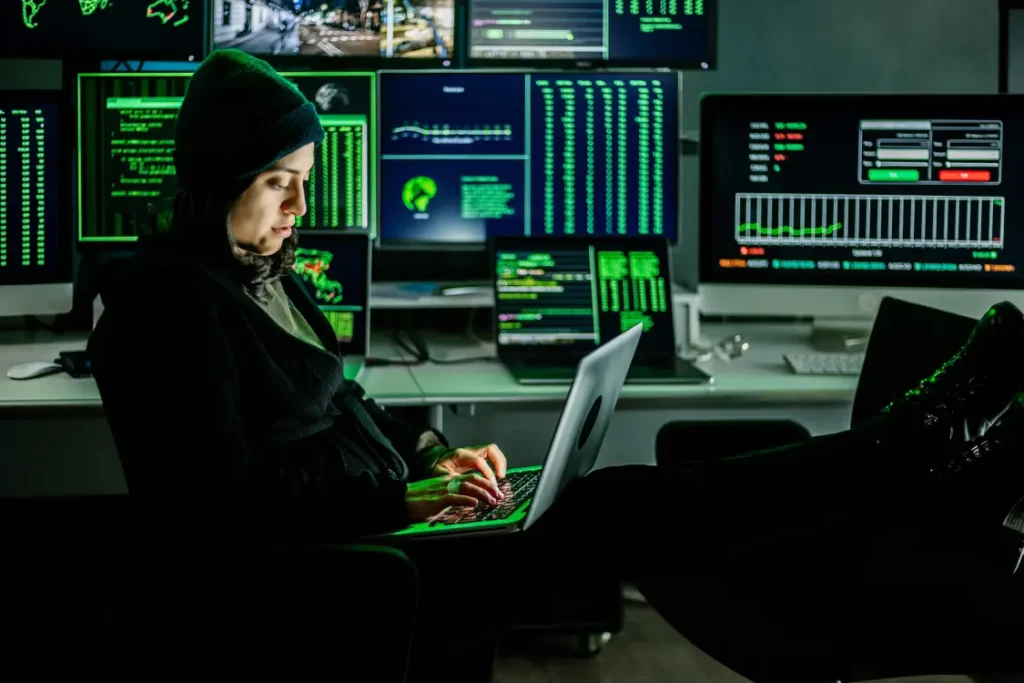 Hacker em uma sala cheia de computadores, trabalhando em um laptop